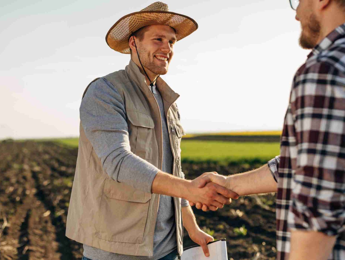 Farmer shakes hands with his business partner in the field